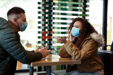 Couple with disposable masks in cafe. Virus protection