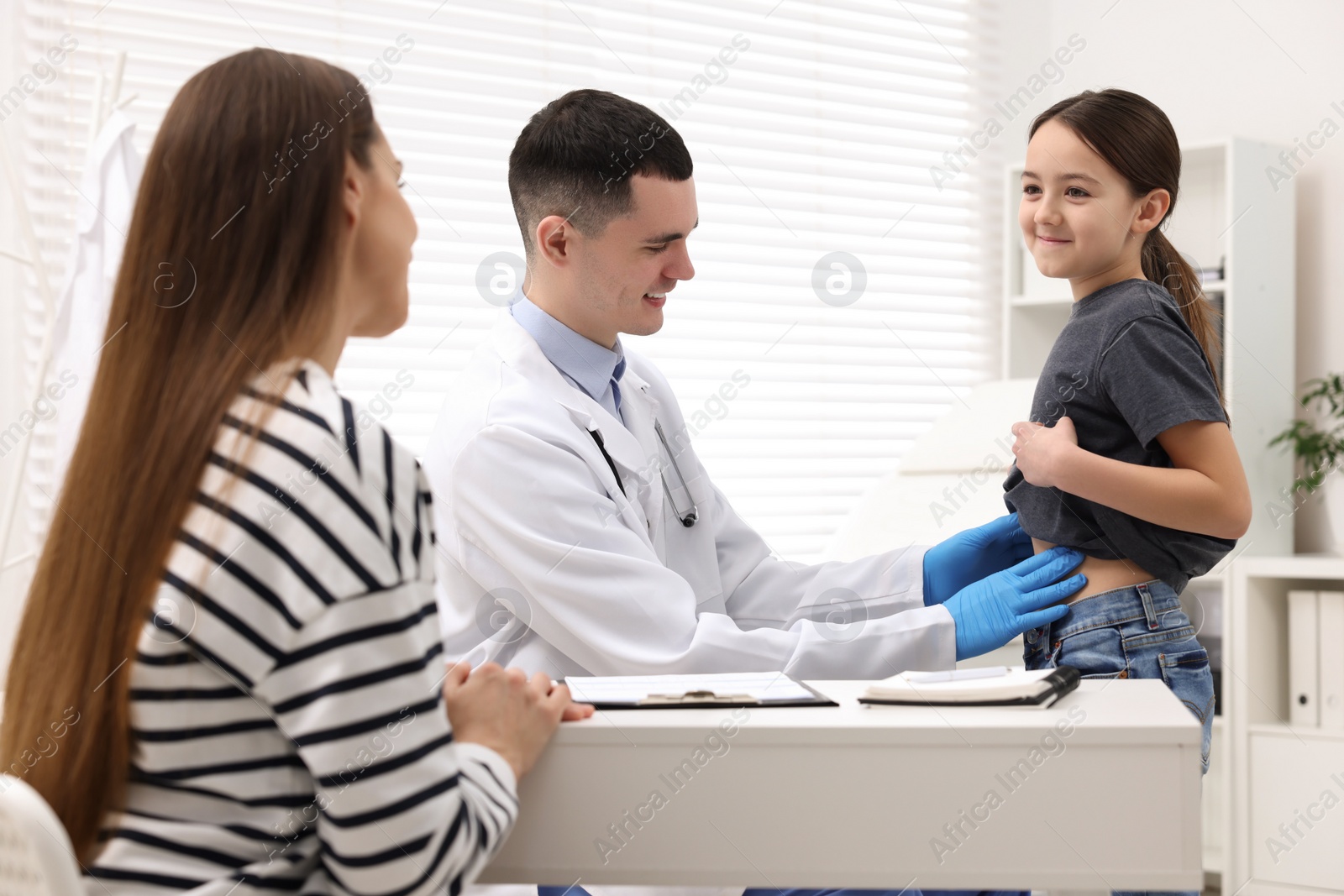 Photo of Gastroenterologist examining girl with stomach ache in clinic