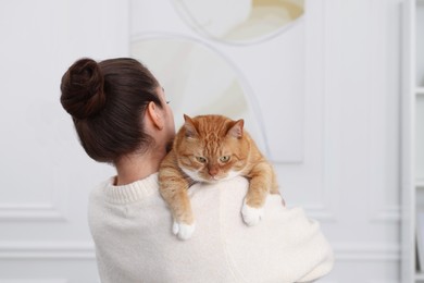 Photo of Woman with cute cat at home, back view