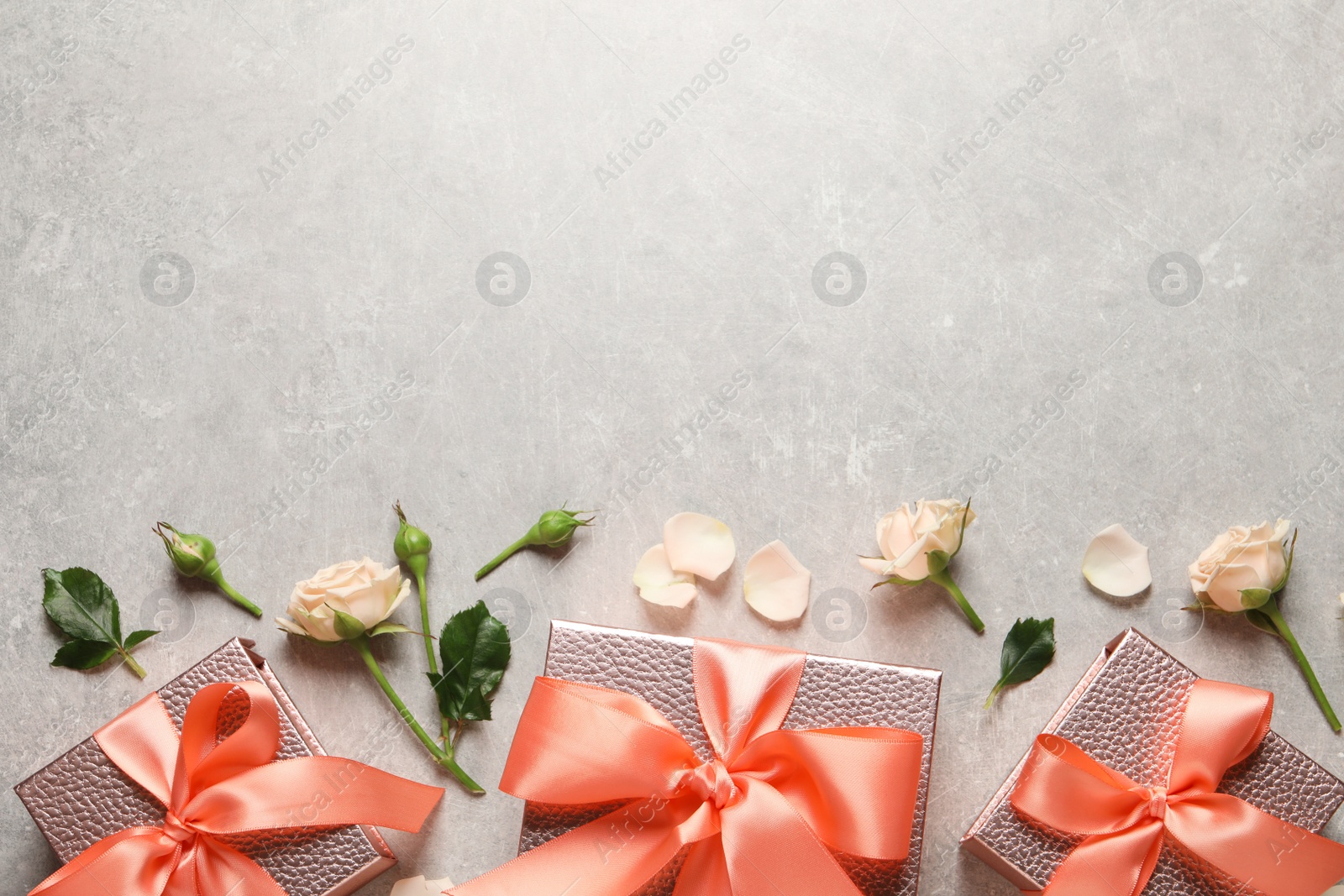 Photo of Pink gift boxes and beautiful roses on grey background, flat lay. Space for text