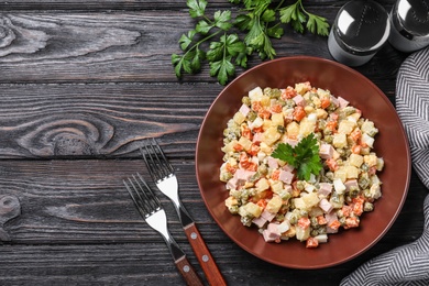 Photo of Delicious salad Olivier on black wooden table, flat lay. Space for text