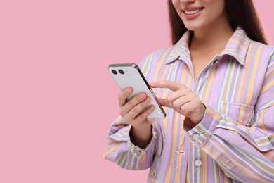Photo of Woman sending message via smartphone on pink background, closeup. Space for text