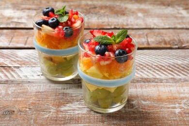 Delicious fruit salad in glasses on wooden table