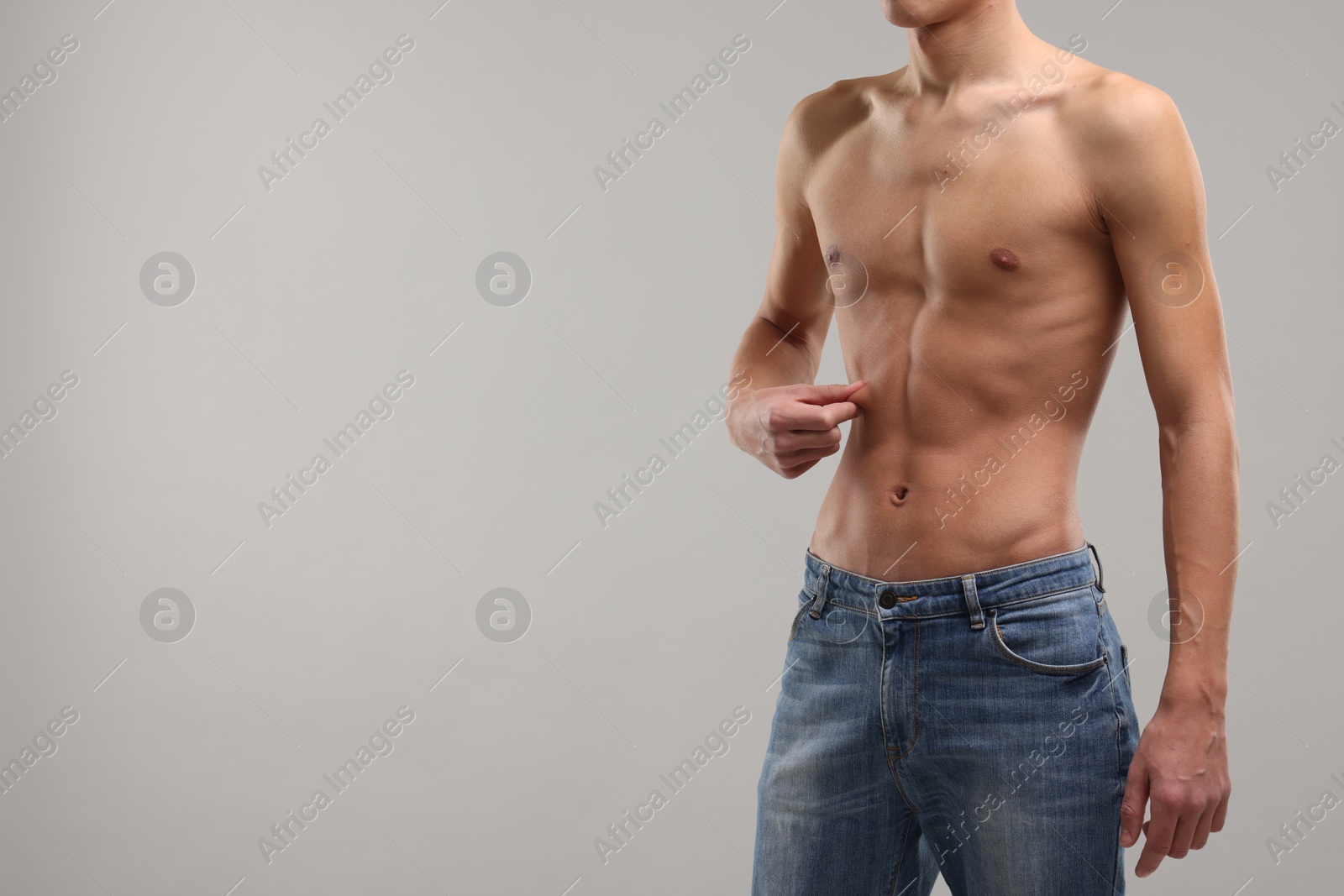 Photo of Shirtless man with slim body on grey background, closeup. Space for text