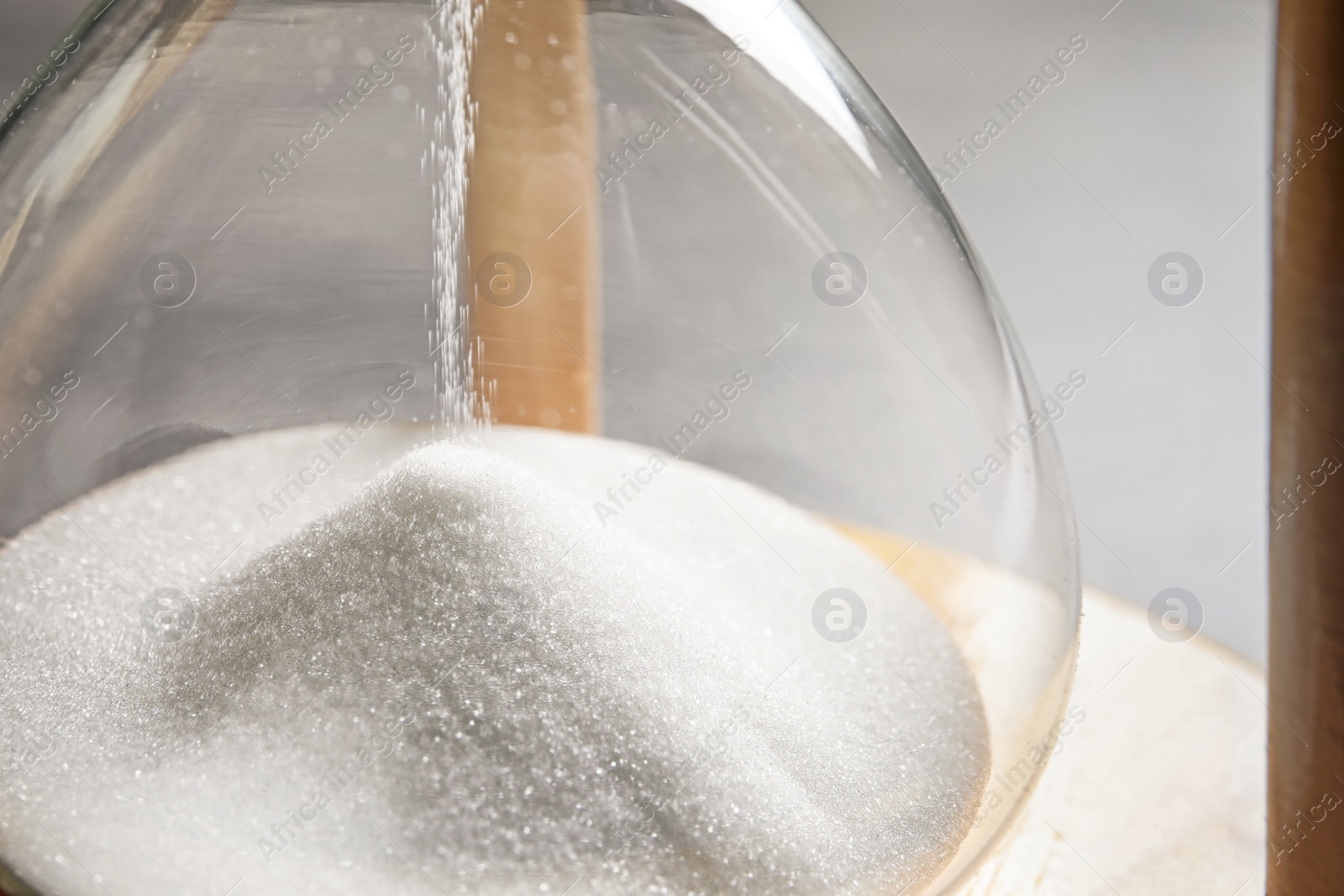 Photo of Hourglass with flowing sand on table, closeup. Time management