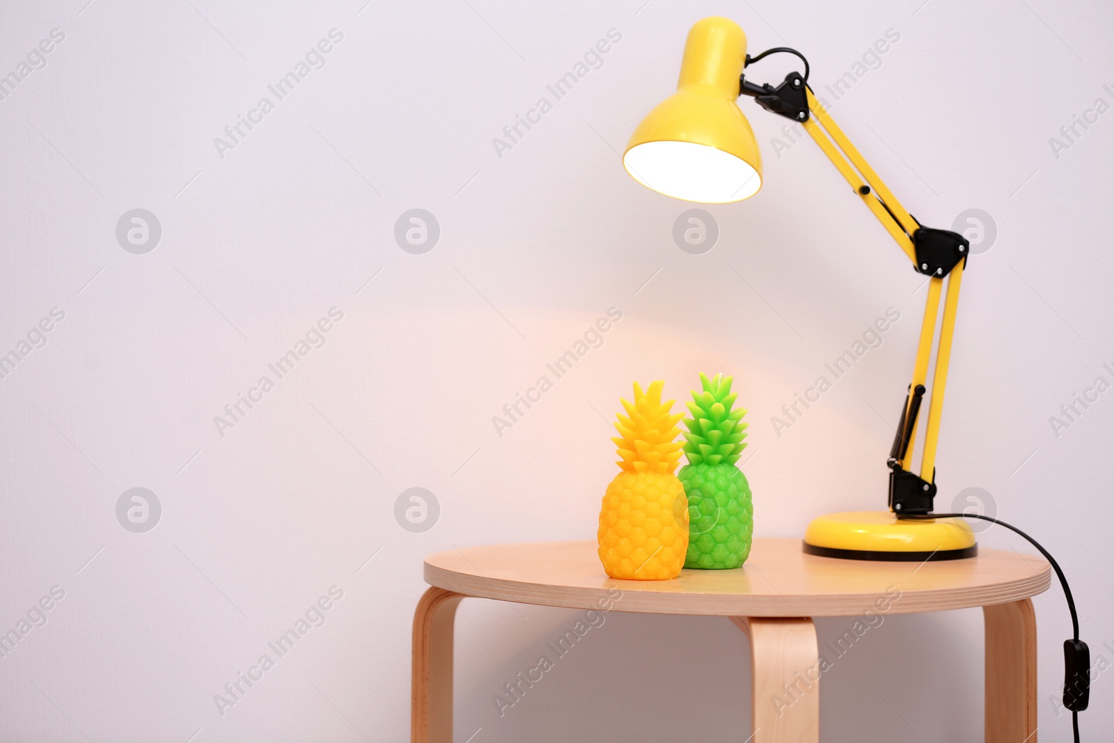 Photo of Stylish pineapple candles and lamp on table. Home decorating idea