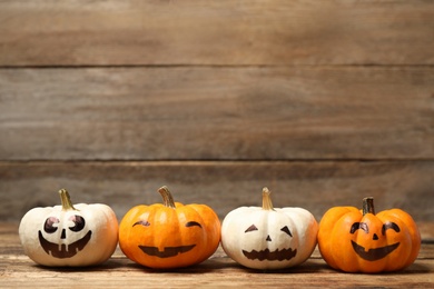 Photo of Pumpkins with scary faces on wooden background, space for text. Halloween decor