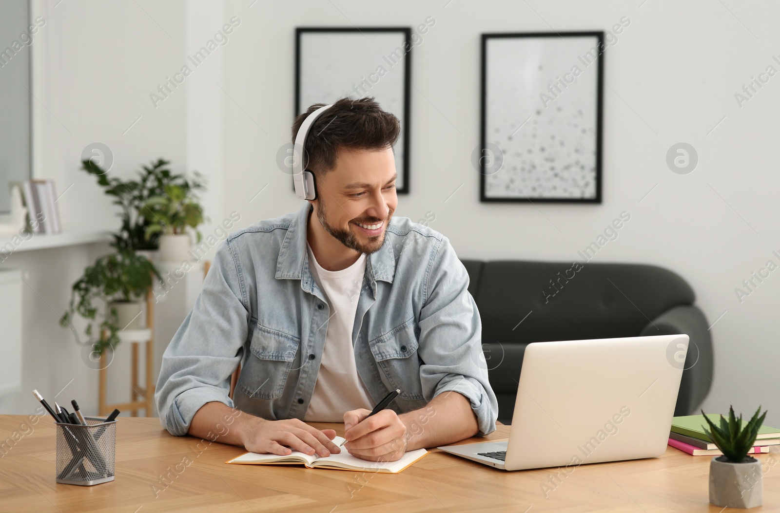 Photo of Man in headphones studying on laptop at home. Online translation course