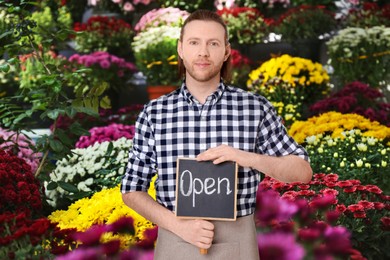 Florist holding sign with text OPEN in shop