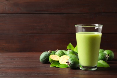 Photo of Fresh feijoa smoothie and fresh fruits on wooden table. Space for text