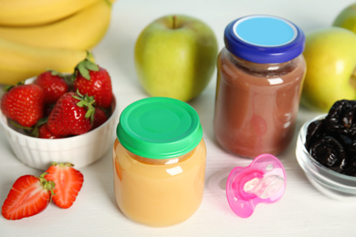 Photo of Jars with baby food and fresh ingredients on white wooden table