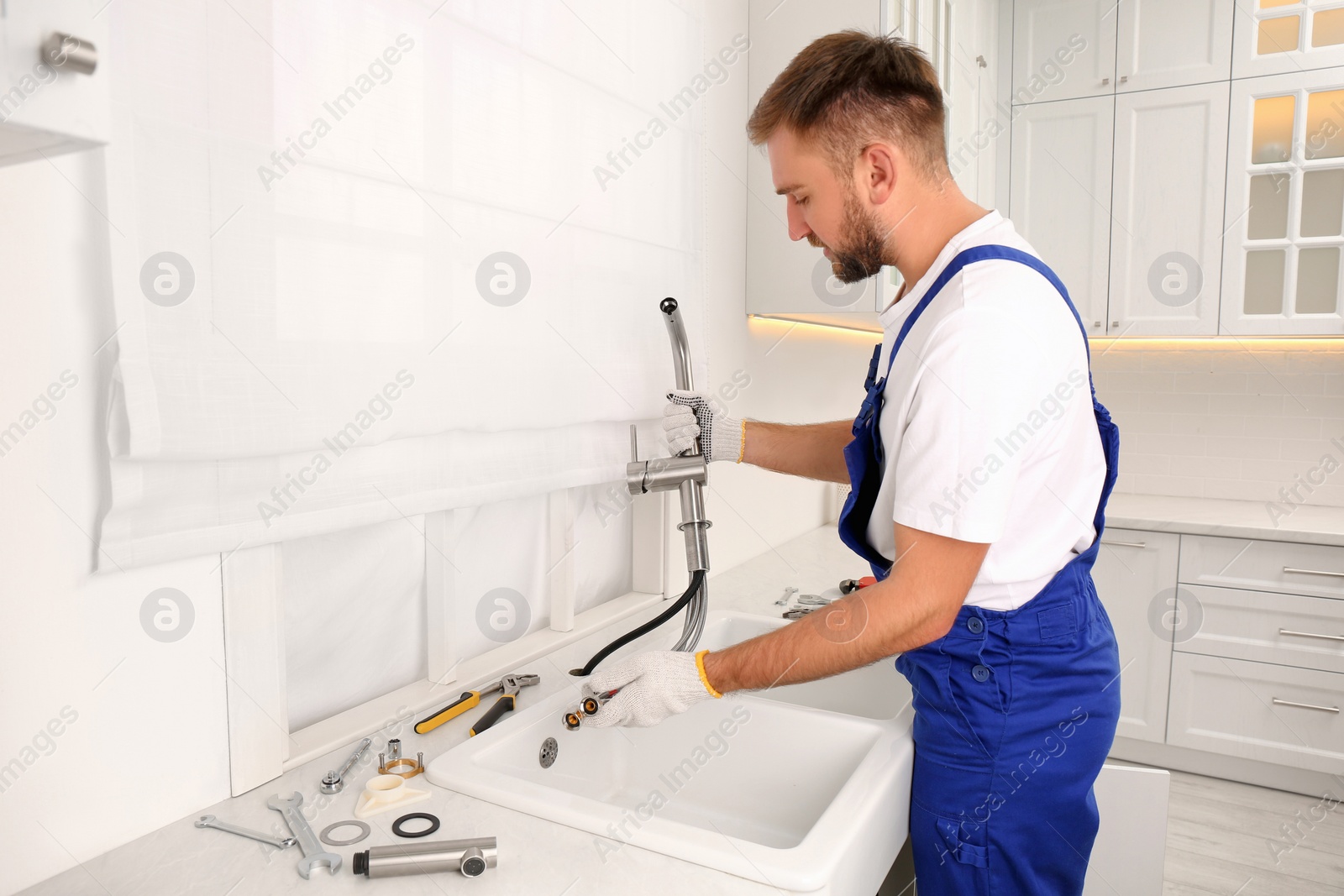 Photo of Professional plumber repairing water tap in kitchen