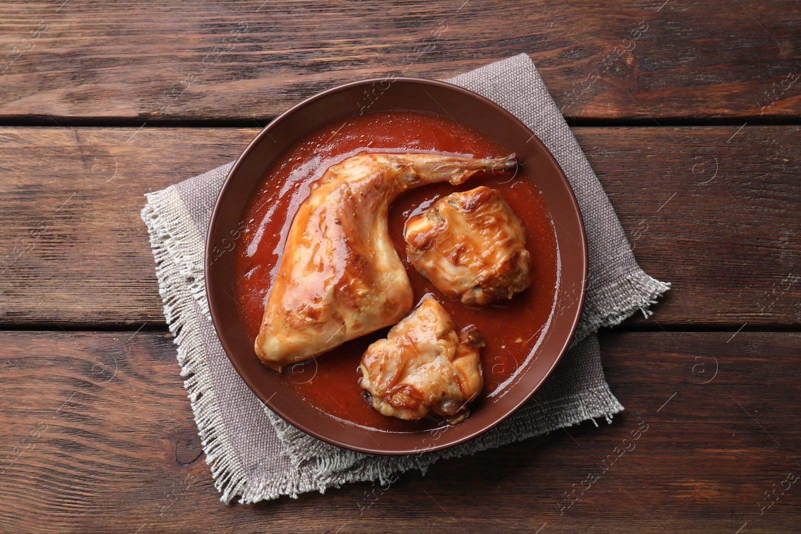Photo of Tasty cooked rabbit meat with sauce on wooden table, top view
