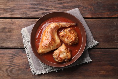 Tasty cooked rabbit meat with sauce on wooden table, top view