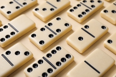 Photo of Classic domino tiles on beige background, closeup