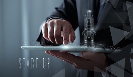 Business startup concept. Man using tablet computer, closeup. Illustration of launching rocket with smoke over device