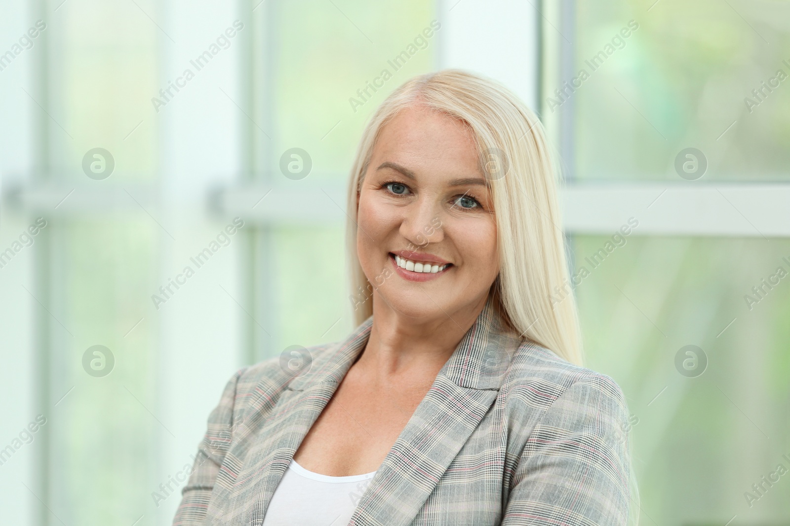 Photo of Portrait of happy mature woman near window indoors