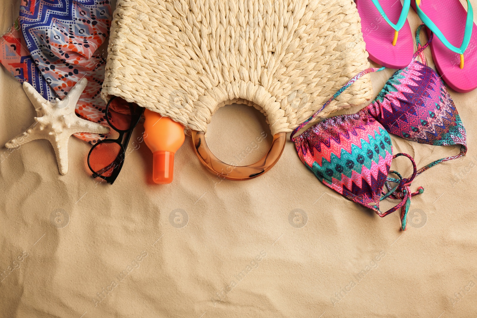 Photo of Different beach accessories on sand, flat lay. Space for text