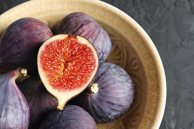 Bowl with fresh ripe figs on dark background, top view