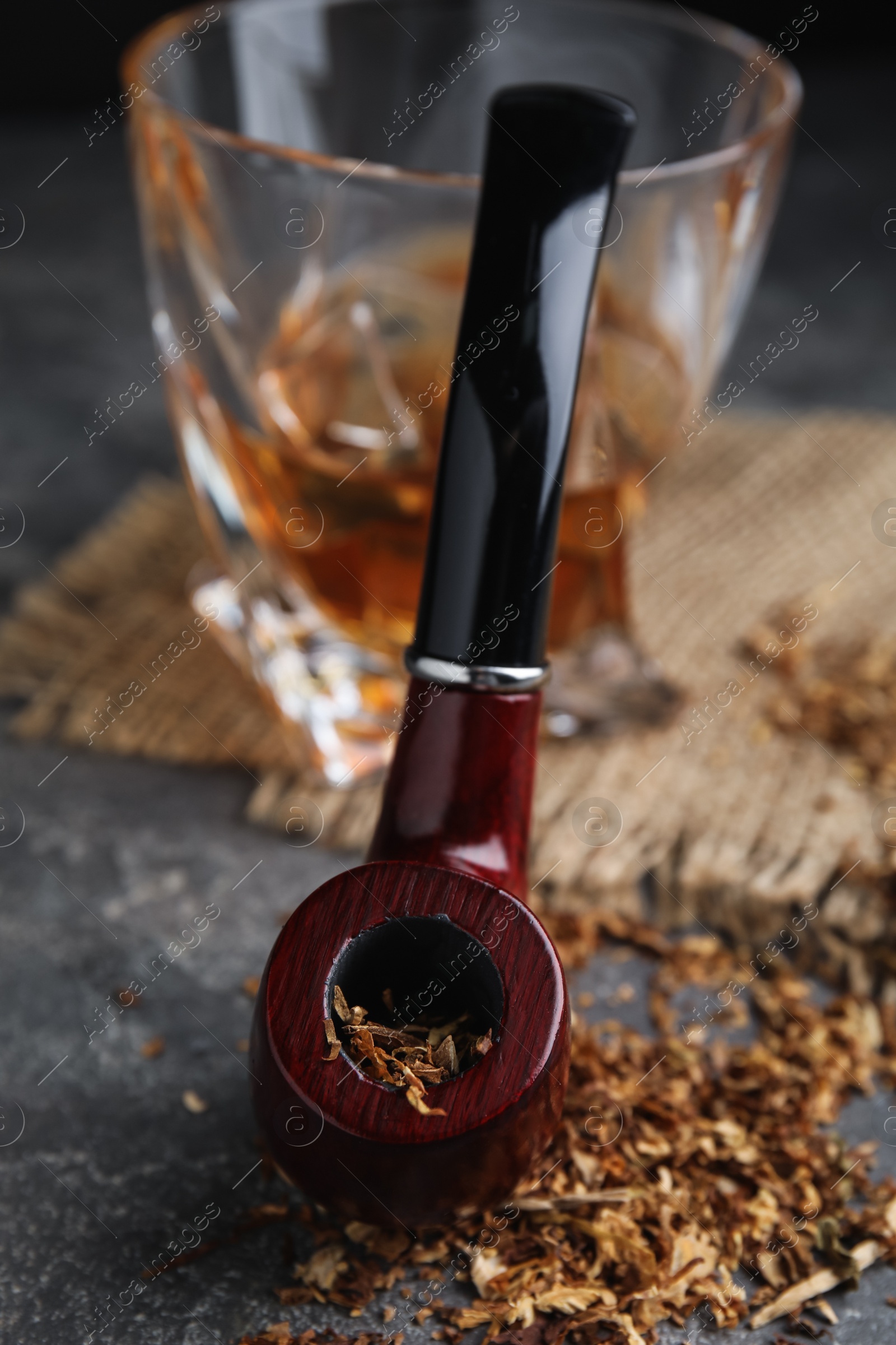 Photo of Smoking pipe with tobacco on grey table