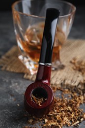 Photo of Smoking pipe with tobacco on grey table