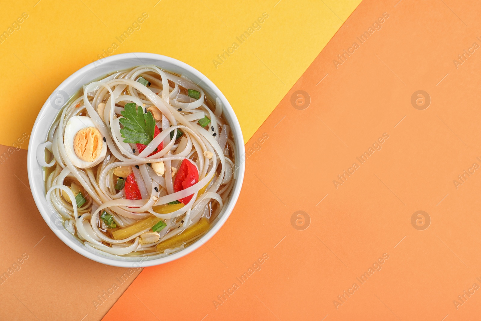 Photo of Tasty ramen with rice noodles and vegetables on color background, top view. Space for text