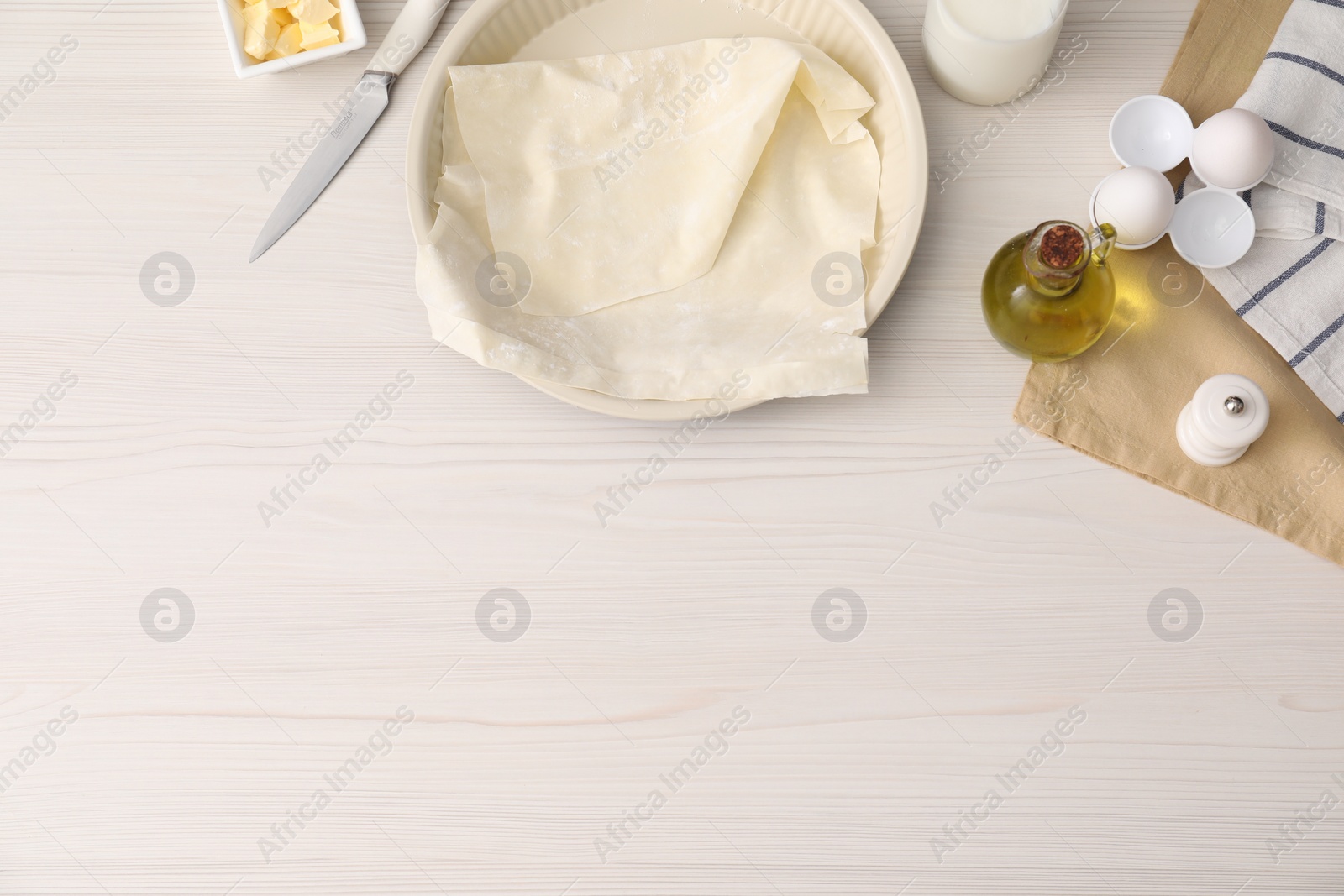 Photo of Fresh dough and different ingredients for making baklava on white wooden table, flat lay. Space for text