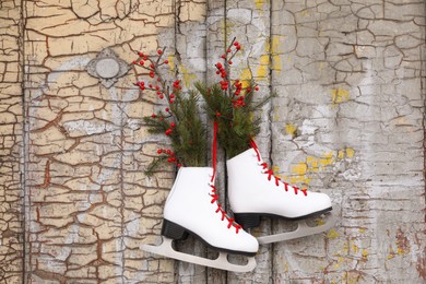 Pair of ice skates with Christmas decor hanging on old wooden door