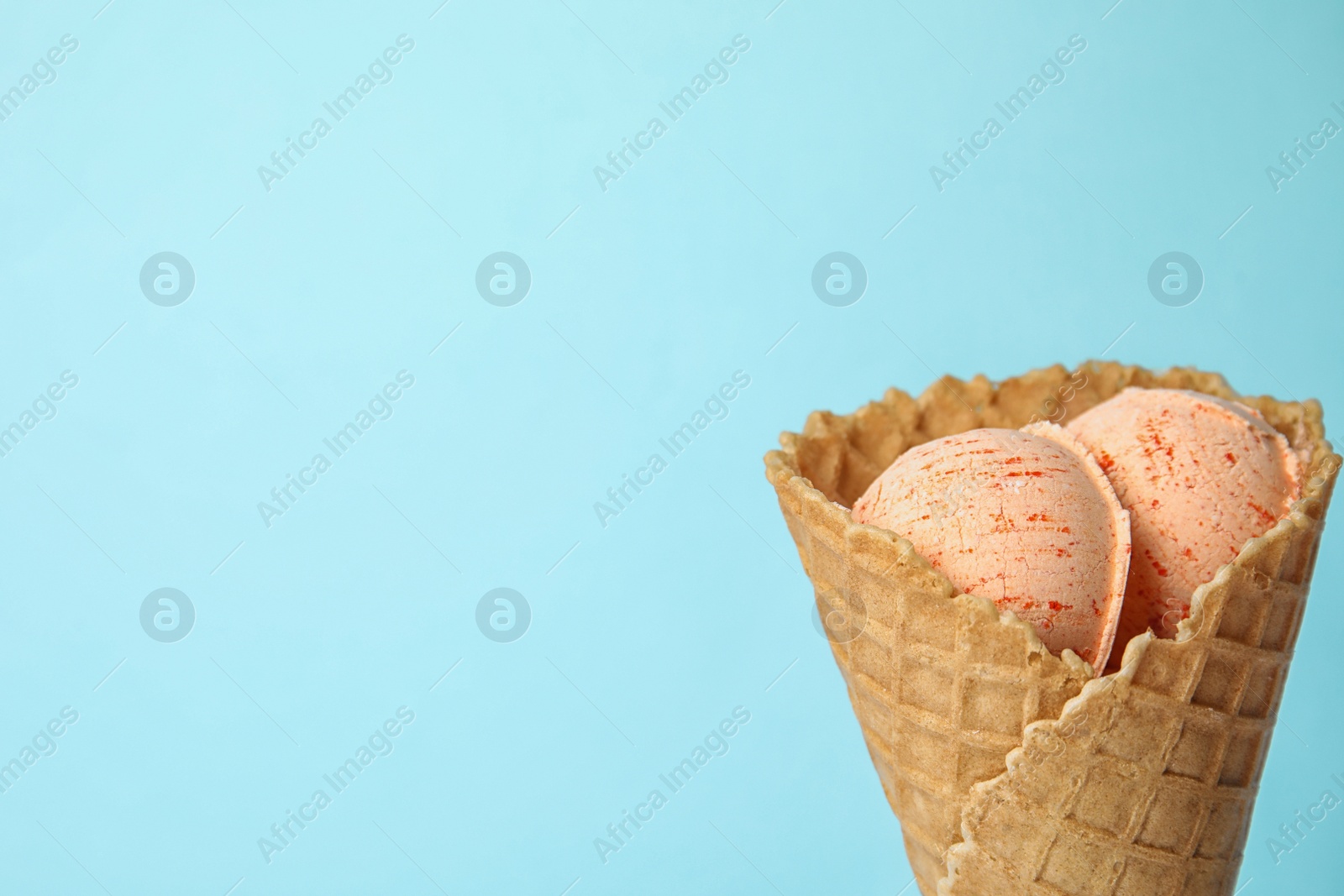 Photo of Delicious ice cream in waffle cone on color background, space for text
