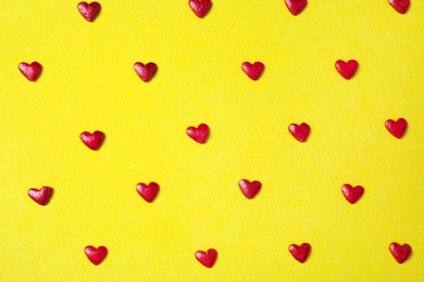 Bright heart shaped sprinkles on yellow background, flat lay