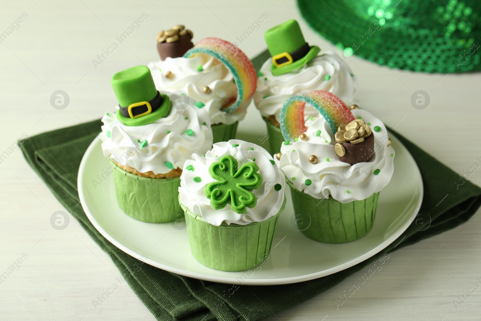 Photo of St. Patrick's day party. Tasty festively decorated cupcakes on white table, closeup