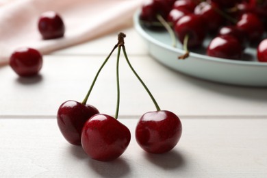 Photo of Sweet red cherries on white wooden table, closeup