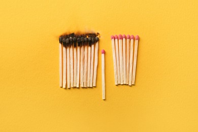 Burnt and whole matches on yellow background, flat lay