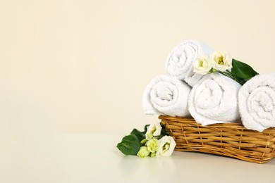 Soft folded towels and flowers on white table, space for text
