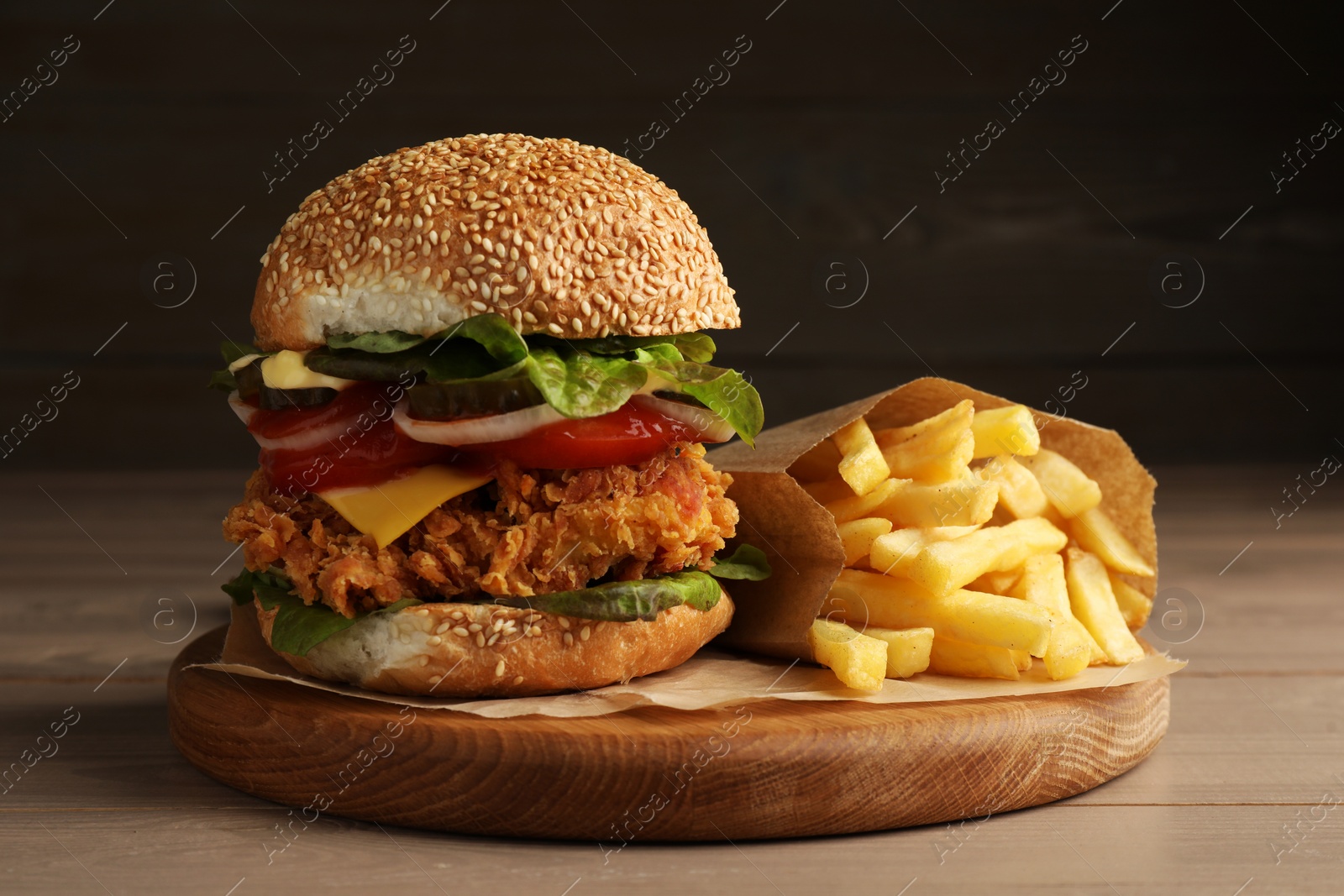 Photo of Delicious burger with crispy chicken patty and french fries on wooden table