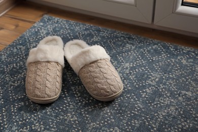 Photo of Pair of beautiful soft slippers on mat indoors. Space for text