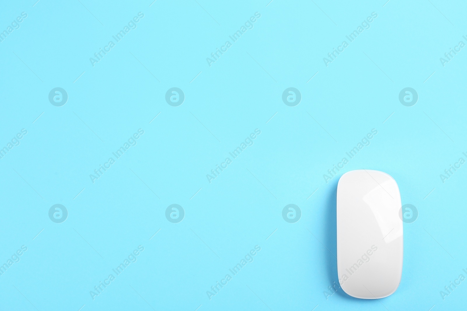 Photo of Modern wireless optical mouse on light blue background, top view. Space for text