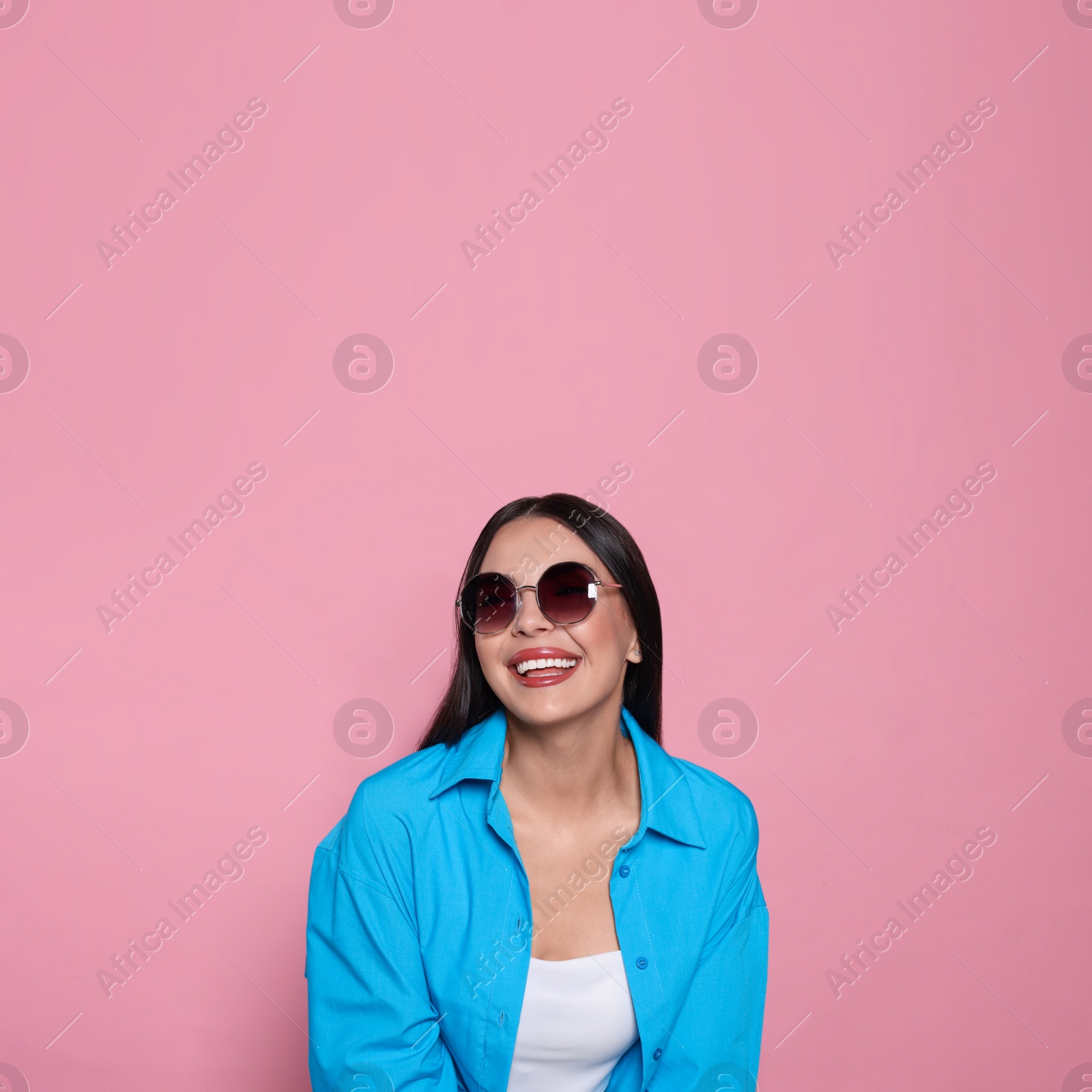 Photo of Attractive happy woman in fashionable sunglasses against pink background