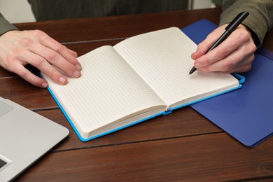 Photo of Man taking notes at wooden table, closeup