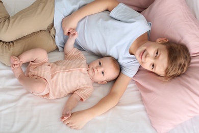 Photo of Cute little baby with elder brother lying on bed at home