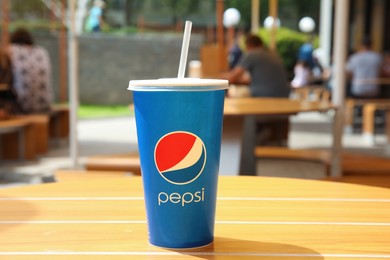 MYKOLAIV, UKRAINE - JUNE 9, 2021: Paper Pepsi cup on wooden table outdoors