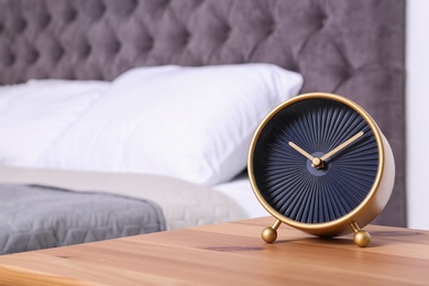 Stylish alarm clock on nightstand in bedroom. Space for text