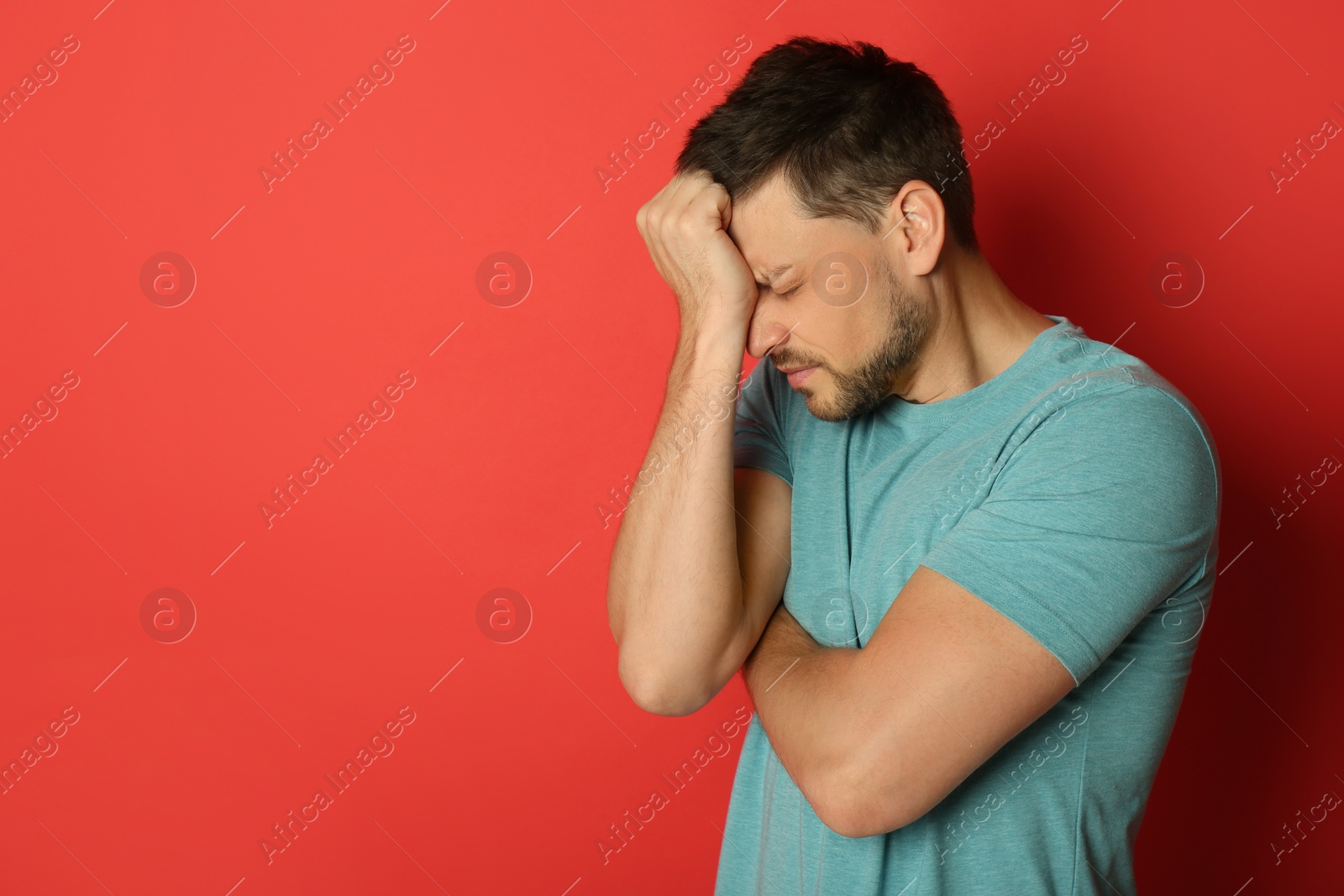 Photo of Man suffering from terrible migraine on red background. Space for text