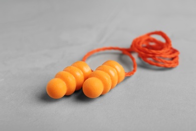 Photo of Pair of orange ear plugs with cord on grey background, closeup