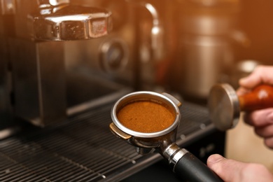 Male barista making espresso using professional coffee machine, closeup