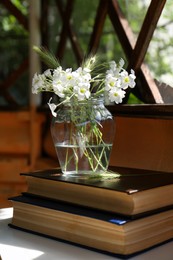 Photo of Bouquet of beautiful wildflowers and books on white table