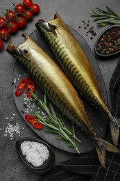 Delicious smoked mackerels and spices on dark grey table, flat lay