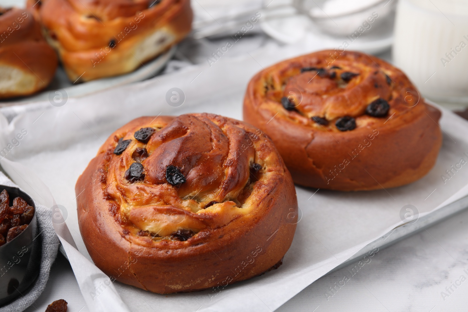 Photo of Delicious rolls with raisins on white table, closeup. Sweet buns