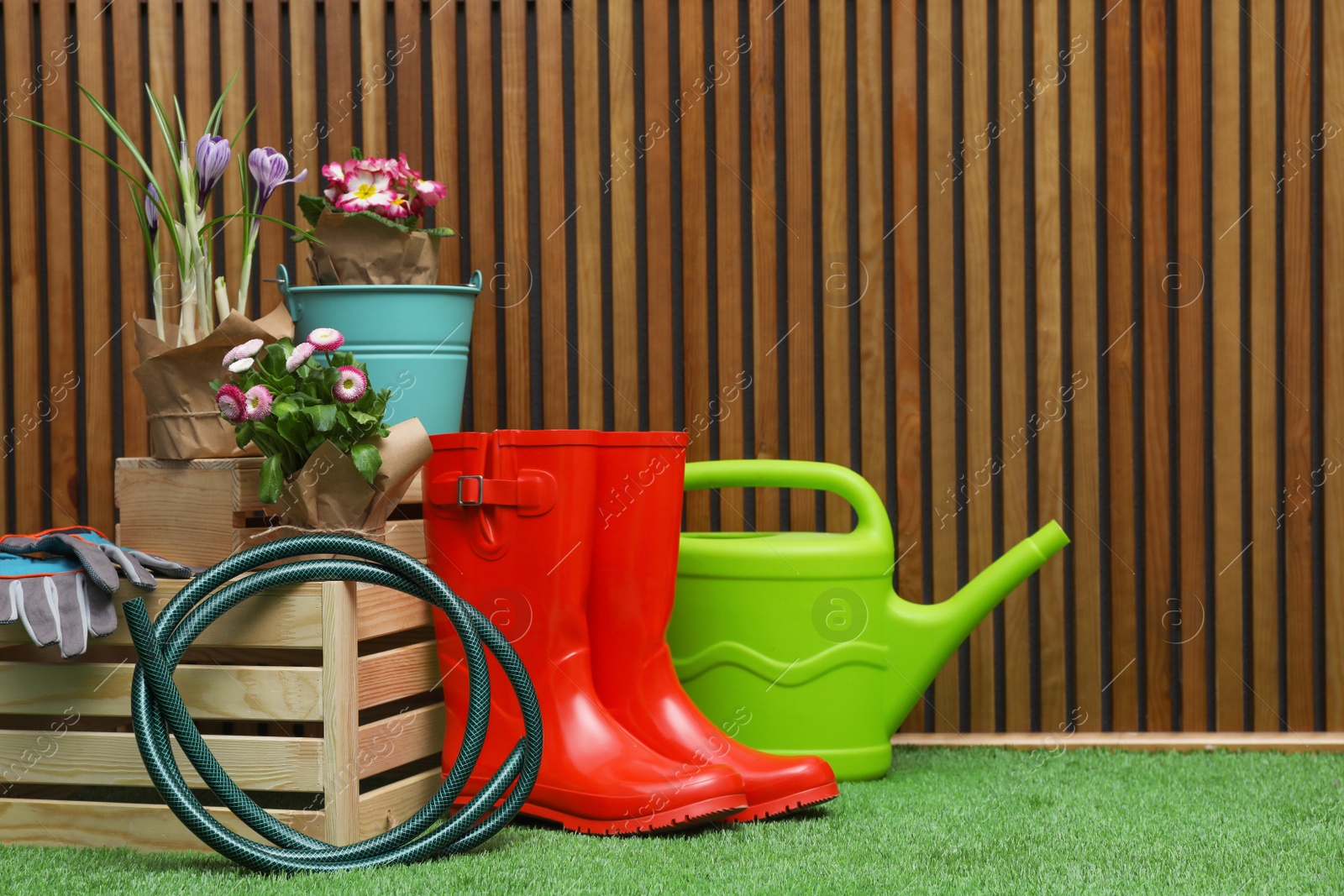 Photo of Composition with different gardening tools on artificial grass at wooden wall. Space for text