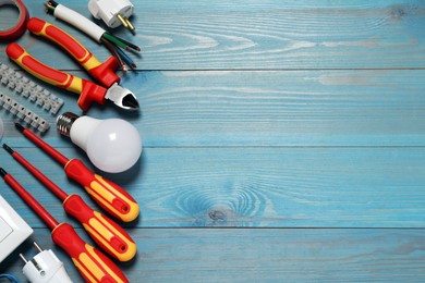 Set of electrician's tools and accessories on light blue wooden table, flat lay. Space for text